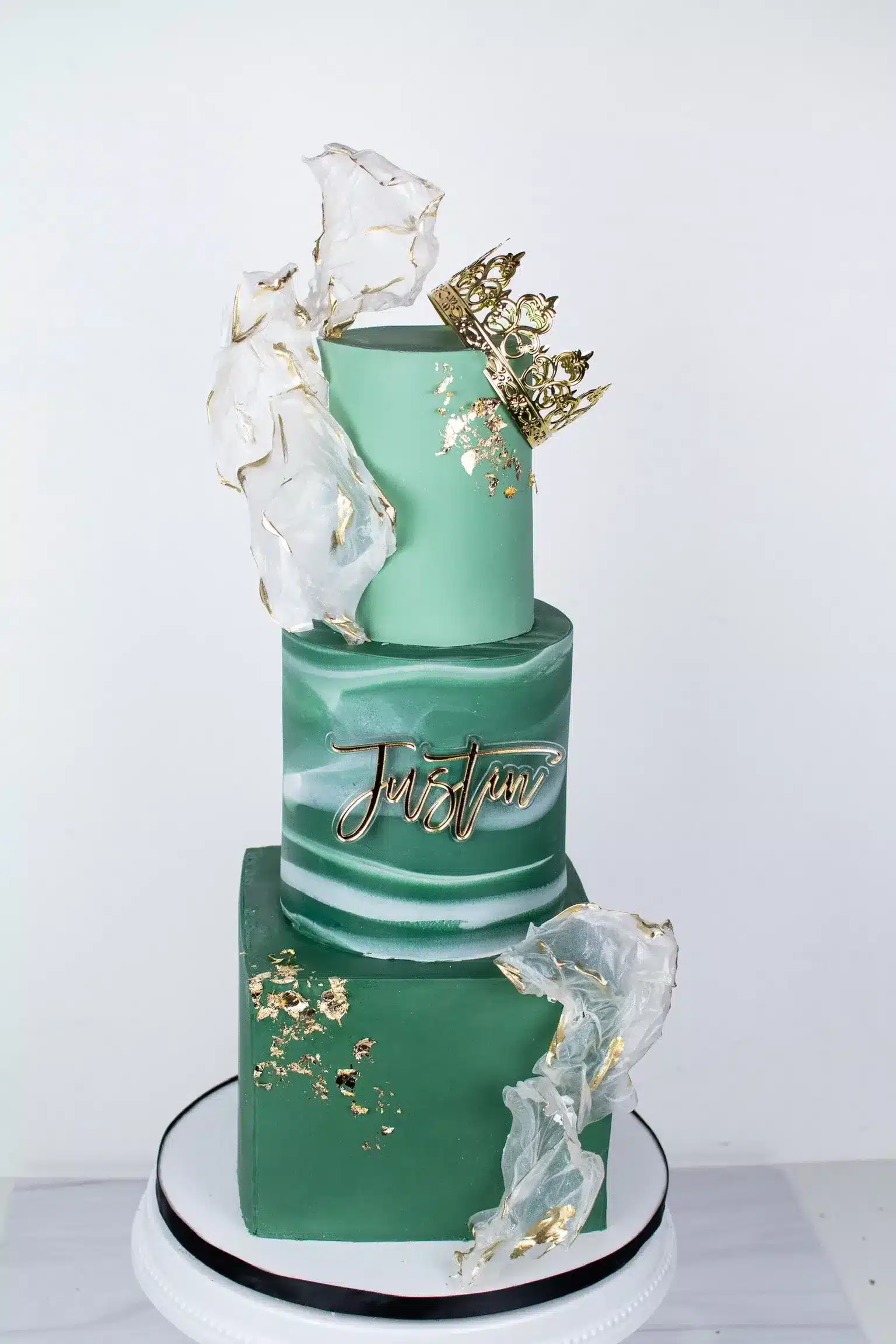 Elegant green and gold tiered wedding cake with floral accents and lace details, perfect for weddings or formal events.