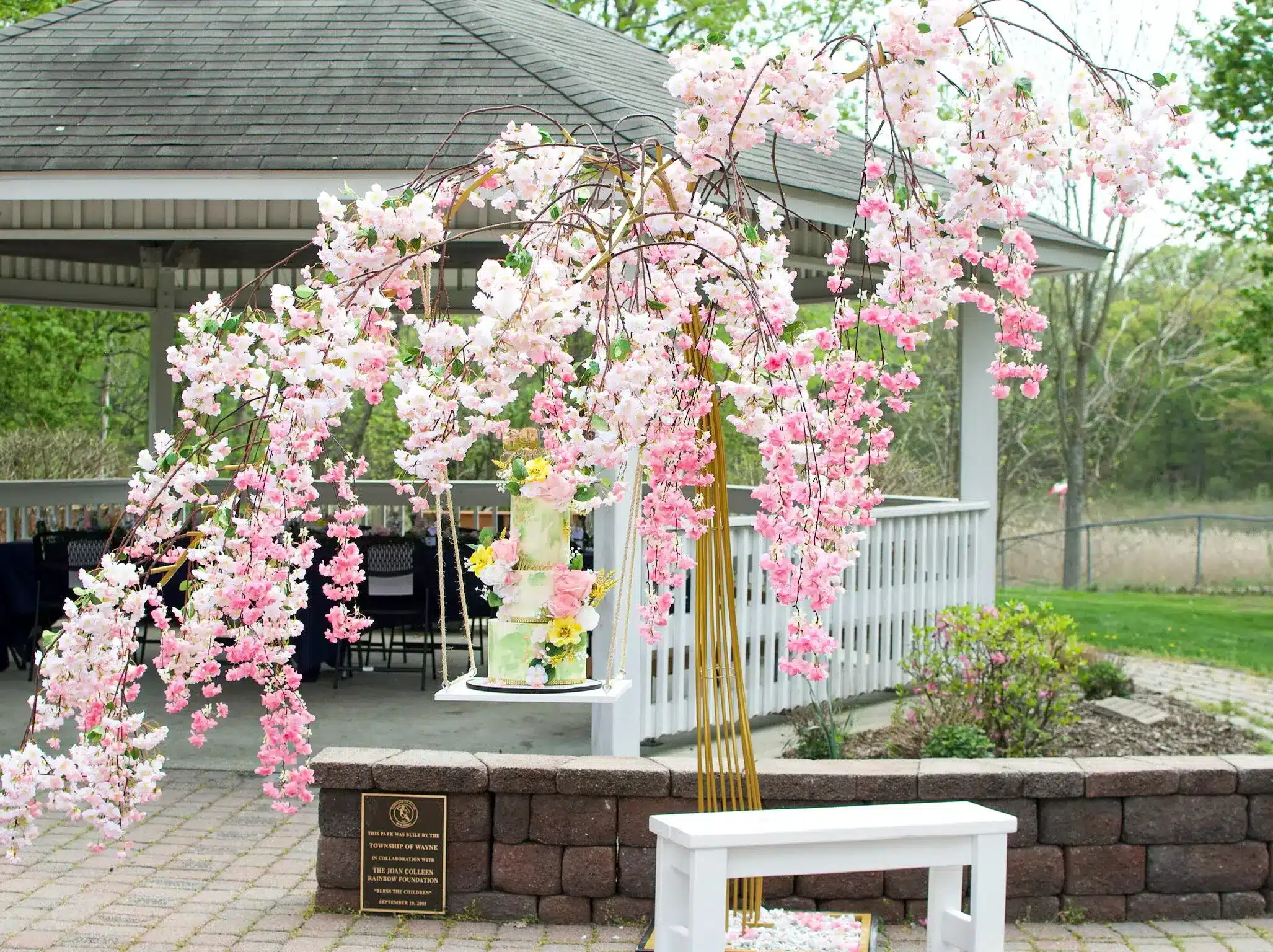 White buttercream wedding cake adorned with cascading pink and white flowers, ideal for spring or summer outdoor weddings.
