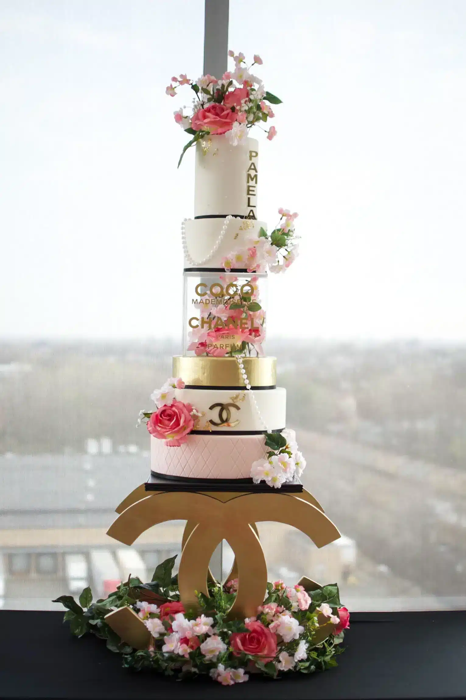 Five-tier wedding cake with pink and white flowers cascading down, ideal for rustic or outdoor-themed weddings.
