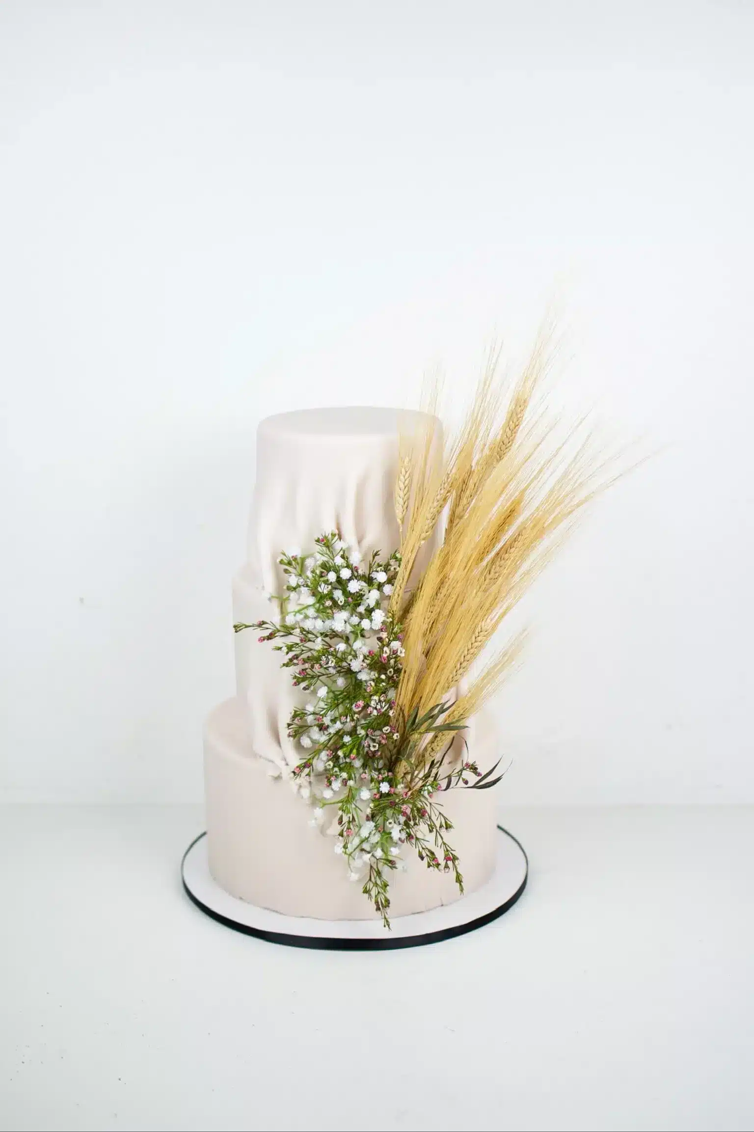 Rustic two-tier buttercream cake with boho dried flowers and pampas grass, perfect for outdoor weddings or intimate celebrations.