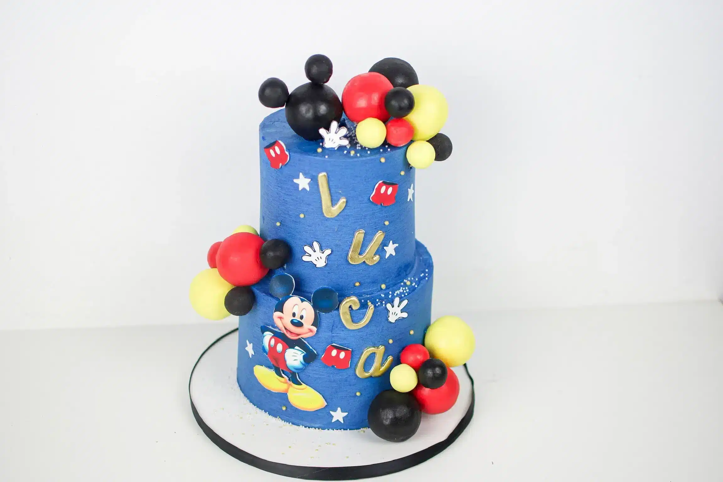 Blue two-tier birthday cake with Mickey Mouse decorations, ideal for Disney-themed celebrations or children's parties.