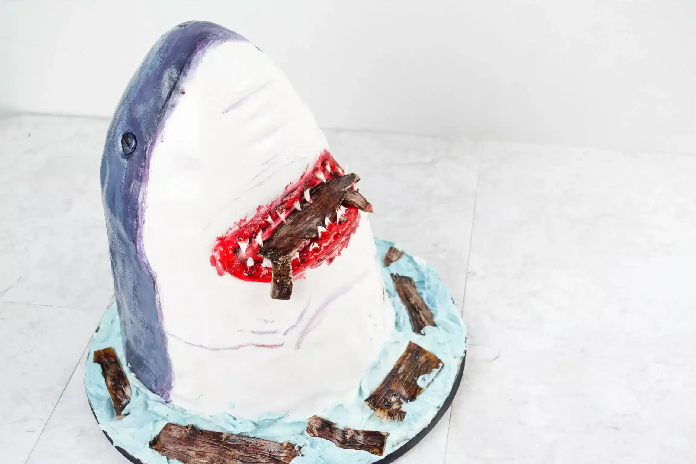 Sculpted shark cake with realistic textures and red accents, ideal for themed events or creative celebrations.