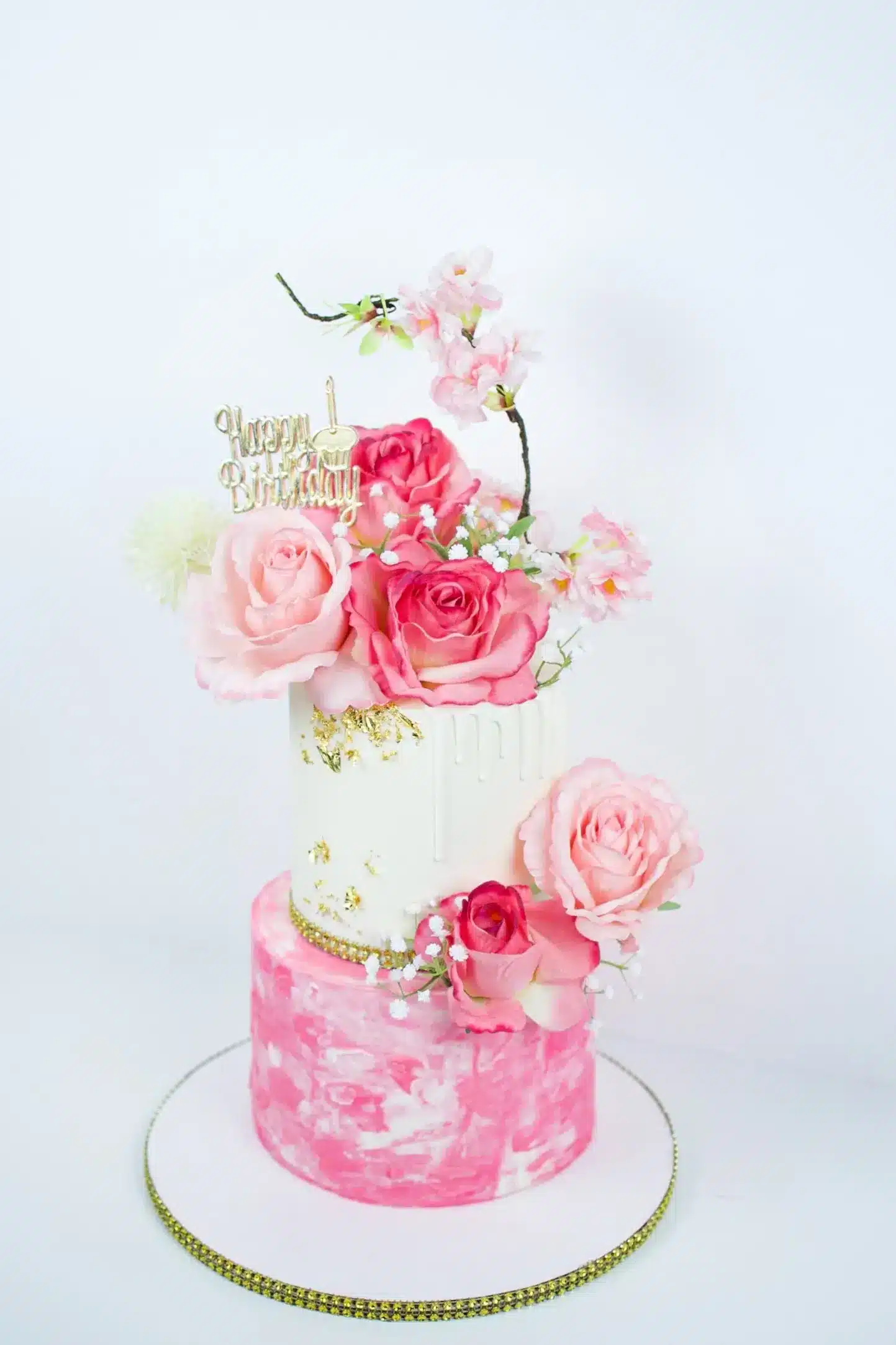 Three-tier pink wedding cake with fresh cascading flowers, perfect for spring or summer weddings.